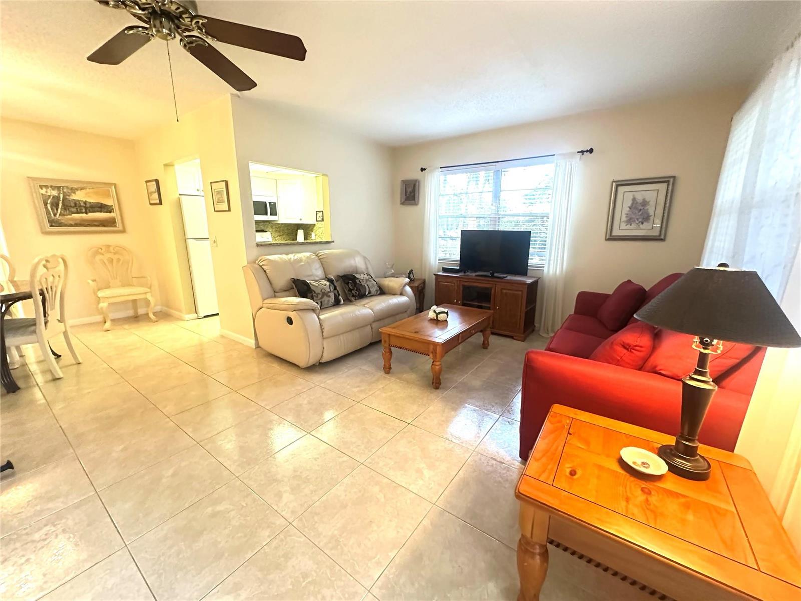 A living room features tile flooring, a ceiling fan, and two sofas facing a television — 489 Tilford W # 489, Deerfield Beach FL 33442, DEERFIELD BEACH, FL