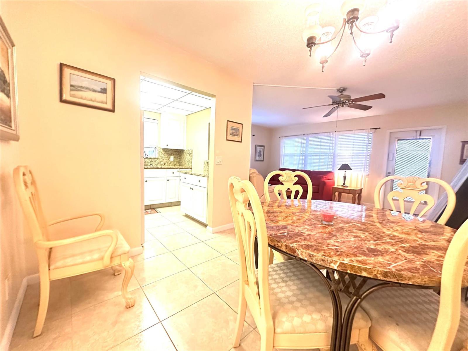 A dining area with a marble-topped table leads into a kitchen with white cabinets — 489 Tilford W # 489, Deerfield Beach FL 33442, DEERFIELD BEACH, FL