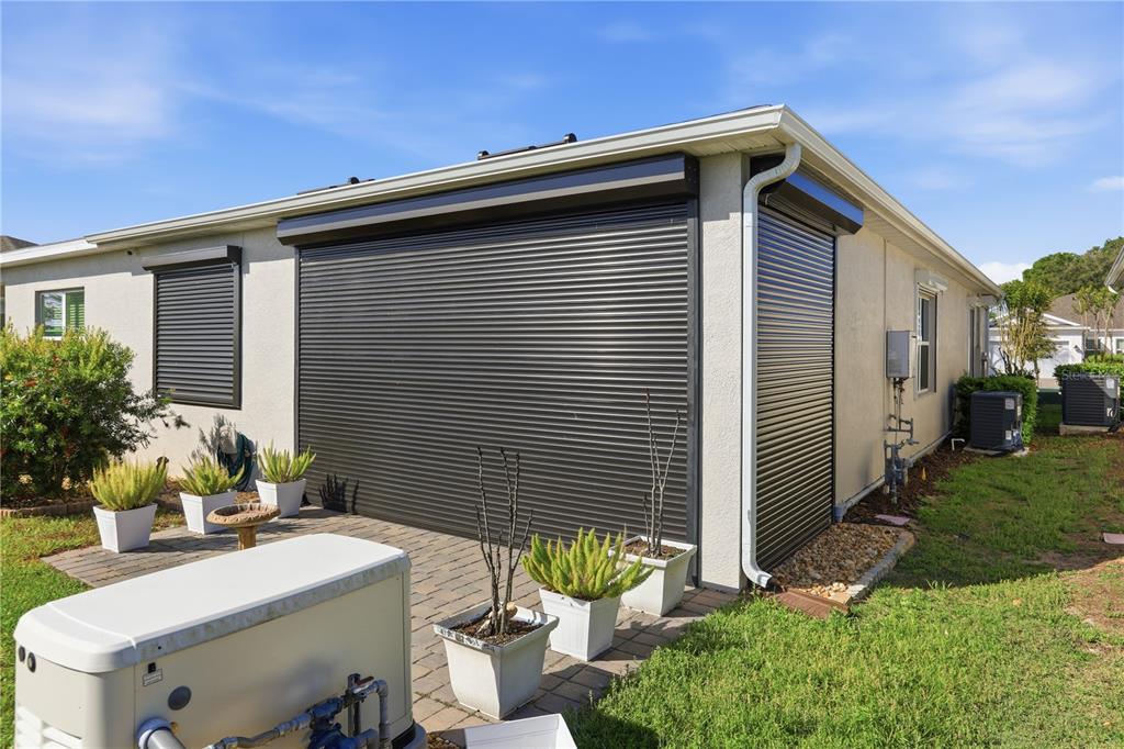 The exterior of a house features black hurricane shutters covering the windows and sliding doors — 1999 KEY BAY TRAIL, KISSIMMEE, FL