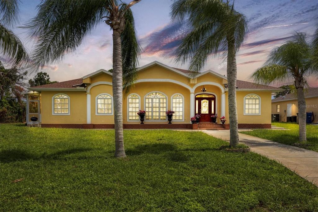A yellow single-story house with a arched entryway and palm trees in the front yard — 12209 COTORRO AVENUE, NORTH PORT, FL