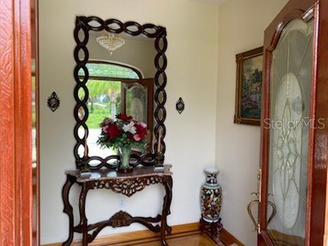 A foyer features a decorative wood console table, a large oval mirror, and a glass-paneled door — 12209 COTORRO AVENUE, NORTH PORT, FL