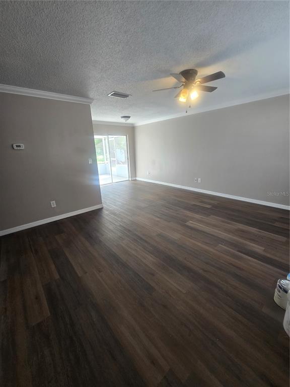An empty living room features dark wood-look flooring, light gray walls, and a ceiling fan — 12470 PRESCOTT STREET, SPRING HILL, FL