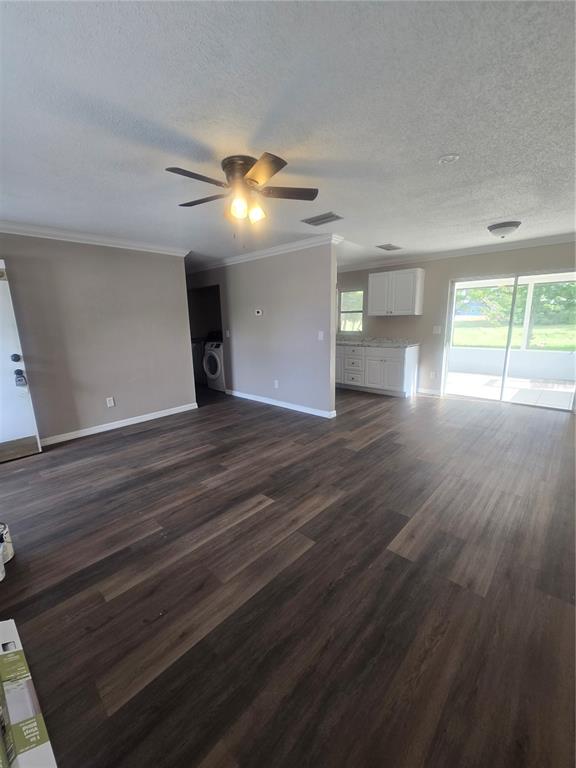 An open-concept living area features dark wood-look flooring, a ceiling fan, and a kitchen — 12470 PRESCOTT STREET, SPRING HILL, FL