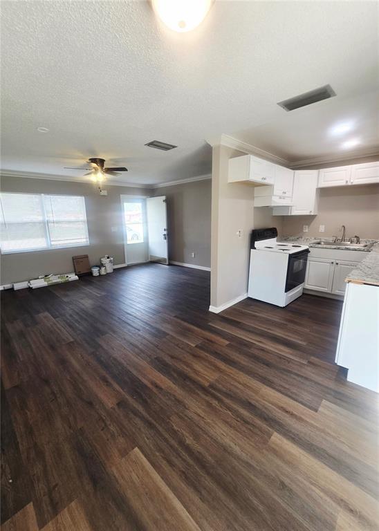 An open-concept kitchen and living area features dark wood-look flooring and white cabinetry — 12470 PRESCOTT STREET, SPRING HILL, FL