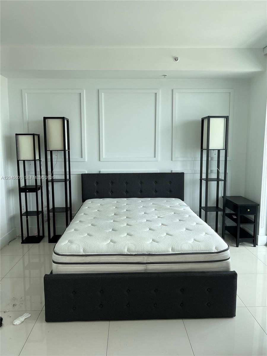 A bedroom features a tufted black bed frame, two tall floor lamps, and white walls — 92 SW 3rd St # 3508, Miami FL 33130, MIAMI, FL