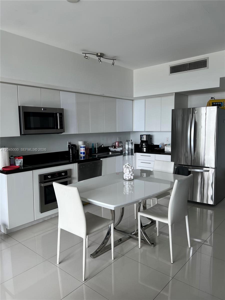 A modern kitchen features white cabinetry, stainless steel appliances, and a white dining table — 92 SW 3rd St # 3508, Miami FL 33130, MIAMI, FL