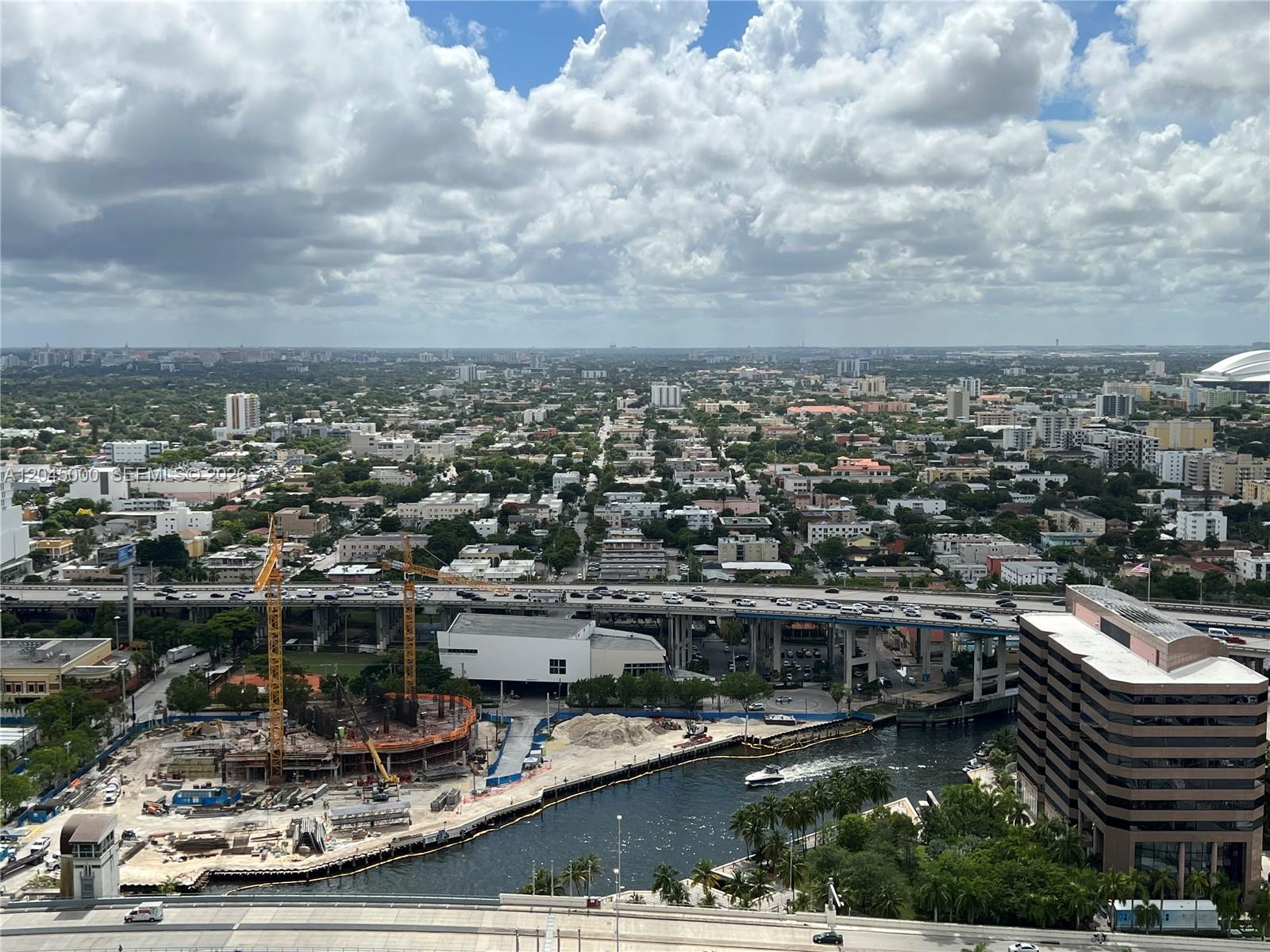 An elevated view of a city skyline featuring a construction site, highway, and waterway — 92 SW 3rd St # 3508, Miami FL 33130, MIAMI, FL