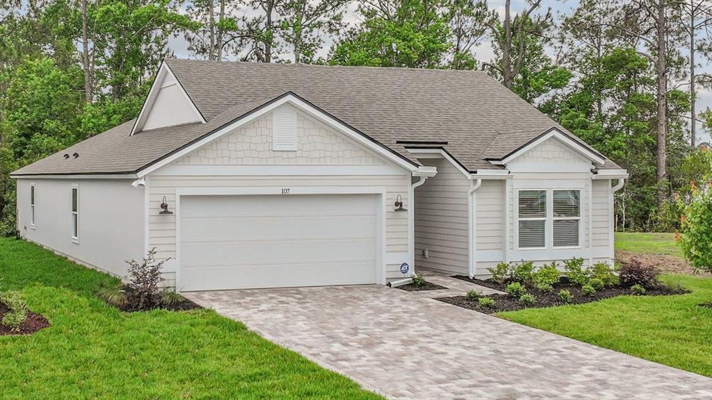 A single-story house with light siding, a two-car garage, and a paved driveway — 107 GREEN CIRCLE, PALM COAST, FL