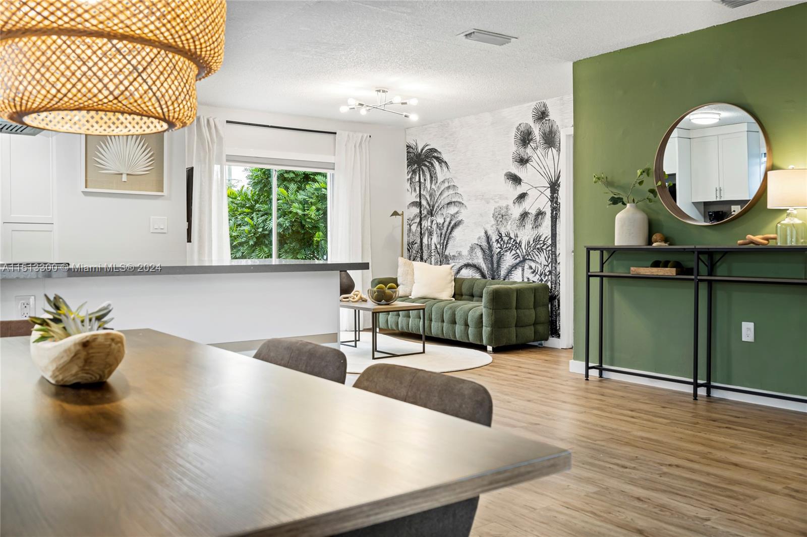 A living and dining area features a green accent wall, palm-print wallpaper, and wood flooring — 20075 SW 87th Pl Side, Cutler Bay FL 33189, CUTLER BAY, FL