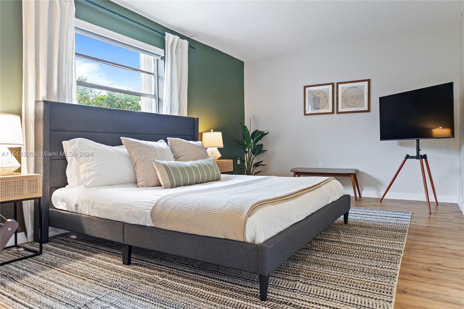 A bedroom features a gray upholstered bed, a green accent wall, and a tripod television stand — 20075 SW 87th Pl Side, Cutler Bay FL 33189, CUTLER BAY, FL