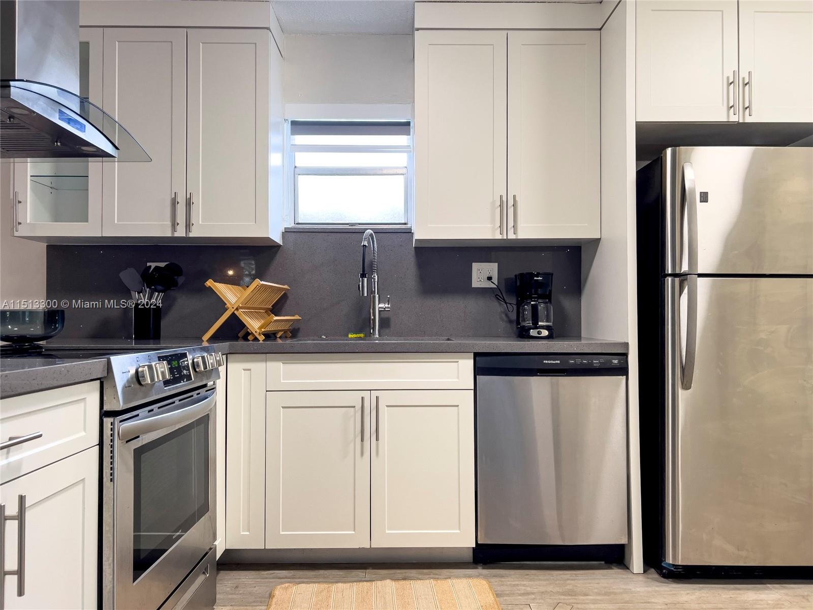 A kitchen features white shaker cabinets, stainless steel appliances, and a dark gray countertop — 20075 SW 87th Pl Side, Cutler Bay FL 33189, CUTLER BAY, FL