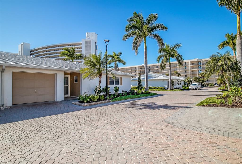 A paved driveway leads to a one-story house with a garage and palm trees — 6300 MIDNIGHT PASS ROAD UNIT 21, SARASOTA, FL