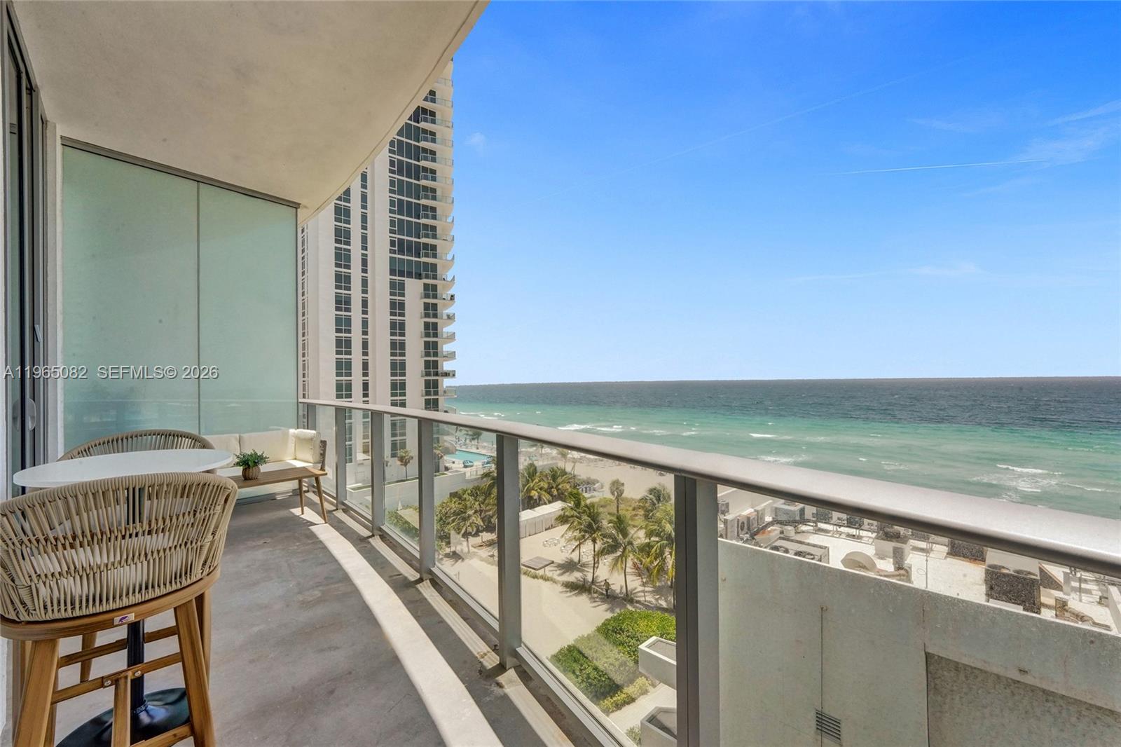 A balcony with outdoor furniture overlooks a beach and the ocean — 4111 S Ocean Dr # 603, Hollywood FL 33019, HOLLYWOOD, FL