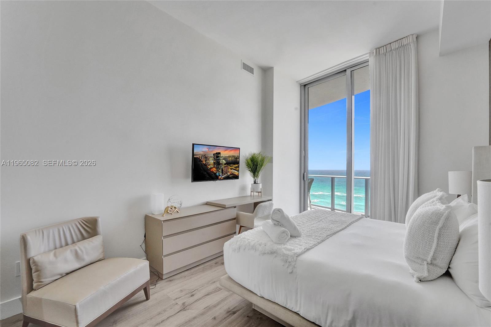 A modern bedroom features a bed, a desk, and a balcony overlooking the ocean — 4111 S Ocean Dr # 603, Hollywood FL 33019, HOLLYWOOD, FL