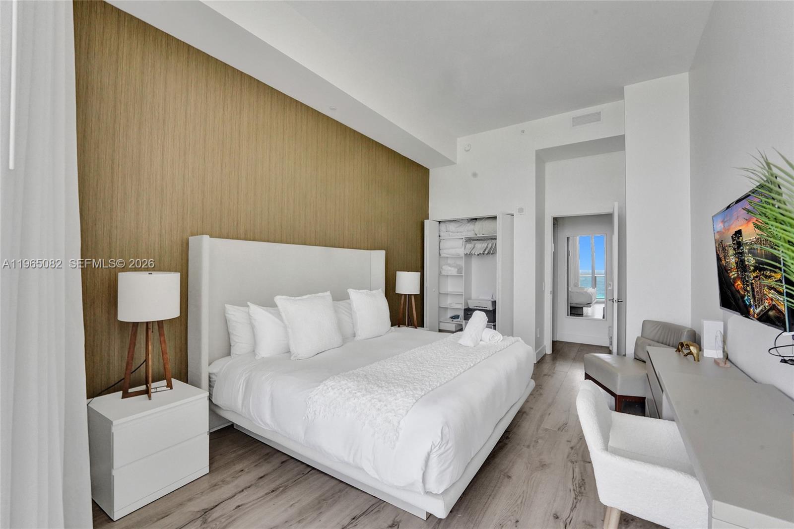 A bedroom features a king bed, wood-paneled accent wall, and a view of the ocean — 4111 S Ocean Dr # 603, Hollywood FL 33019, HOLLYWOOD, FL