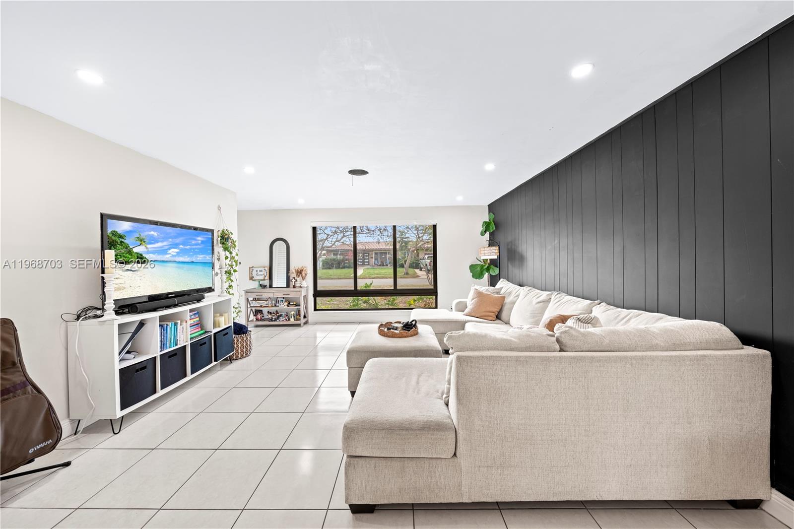 A living room features a large sectional sofa, a white media console, and a black accent wall — 7835 W 16th Ct, Hialeah FL 33014, HIALEAH, FL