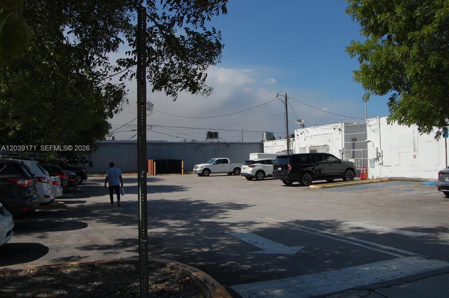 A paved parking lot sits in front of a white industrial building under a blue sky — 1900 e 4th ave, Hialeah FL 33010, HIALEAH, FL