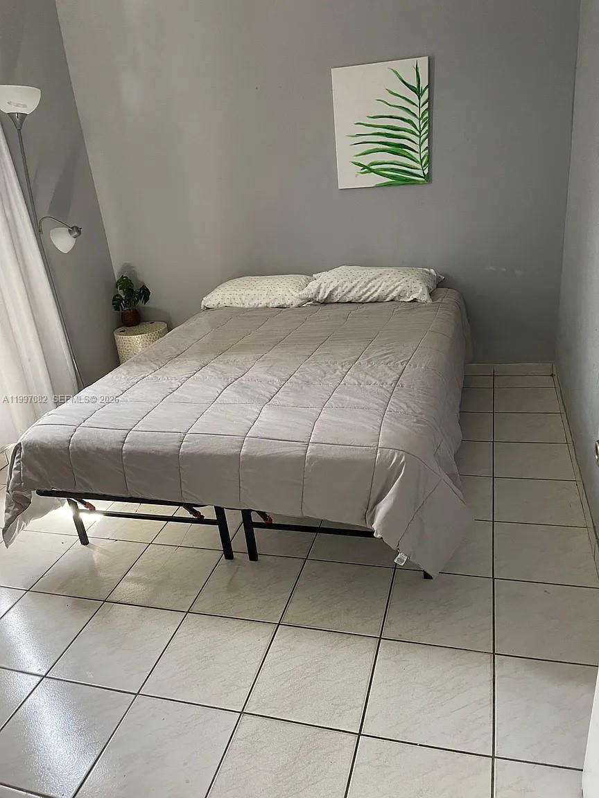 A bedroom features a bed with a grey comforter, tile flooring, and a wall art piece — 638 SW 15th Ave, Miami FL 33135, MIAMI, FL