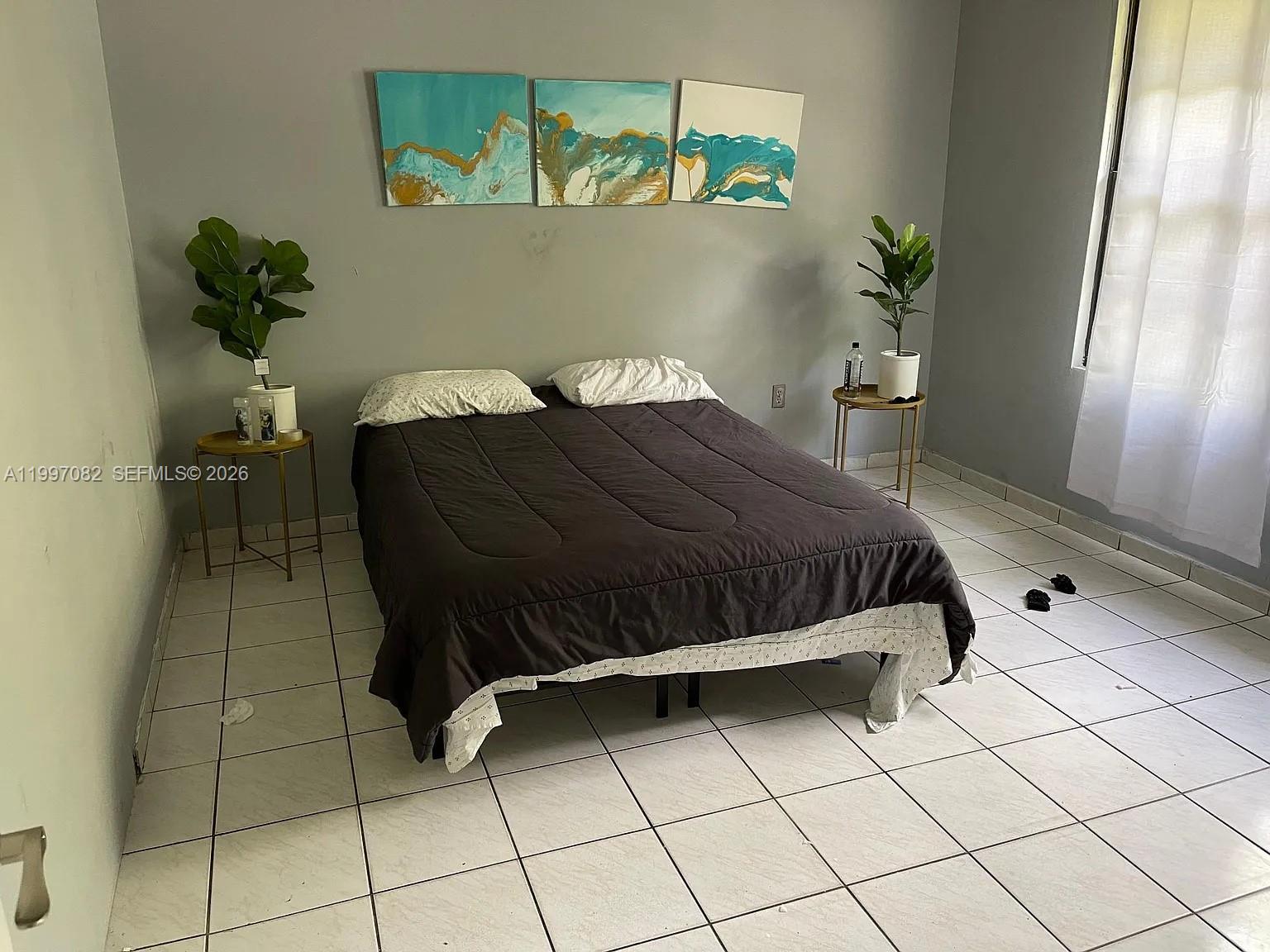 A bedroom features a bed with a dark comforter, two side tables, and wall art — 638 SW 15th Ave, Miami FL 33135, MIAMI, FL