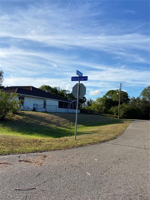 A street corner with a stop sign, street signs, and a house in the background — Lot 19 EMBASSY ROAD, NORTH PORT, FL