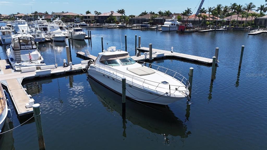 A white motor yacht is docked at a marina with other boats in the background — 102 RIVIERA DUNES WAY UNIT S-55, PALMETTO, FL