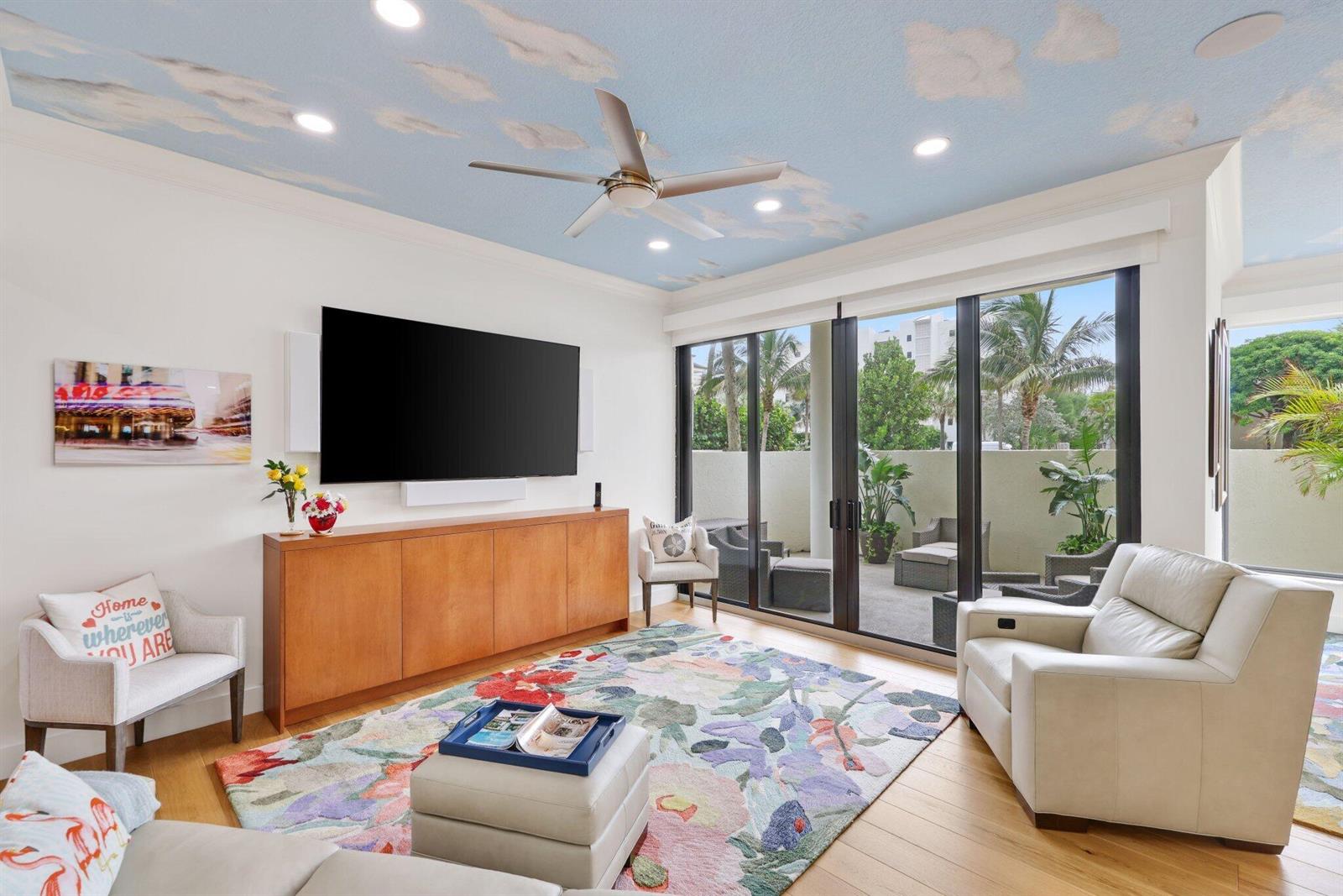 A living room features a cloud-painted ceiling, floral area rug, and sliding glass doors to a patio — 3900 N Ocean Boulevard, Gulf Stream FL 33483, GULF STREAM, FL