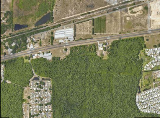 An aerial view shows a large wooded area bordered by roads, agricultural fields, and residential developments — US HIGHWAY 17, HAINES CITY, FL