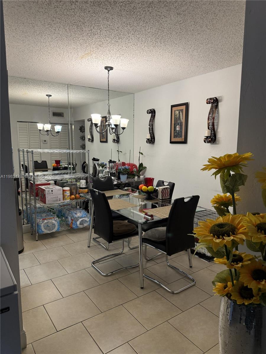 A dining area features a glass table, black chairs, a mirrored wall, and tile flooring — 7845 Miller Dr # A204, Miami FL 33155, MIAMI, FL