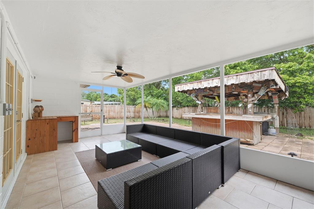 A screened-in patio features tile flooring, a modular wicker sofa, and an outdoor tiki bar — 11105 ARECA DRIVE, PORT RICHEY, FL