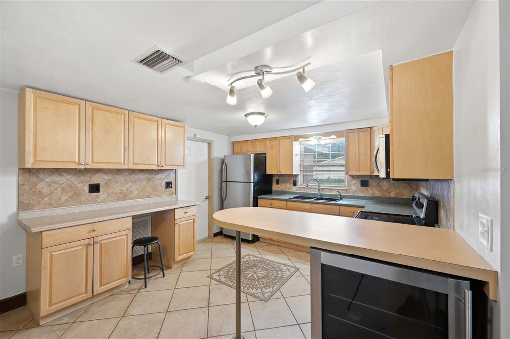 A kitchen features light wood cabinets, tile flooring, a breakfast bar, and stainless steel appliances — 11105 ARECA DRIVE, PORT RICHEY, FL