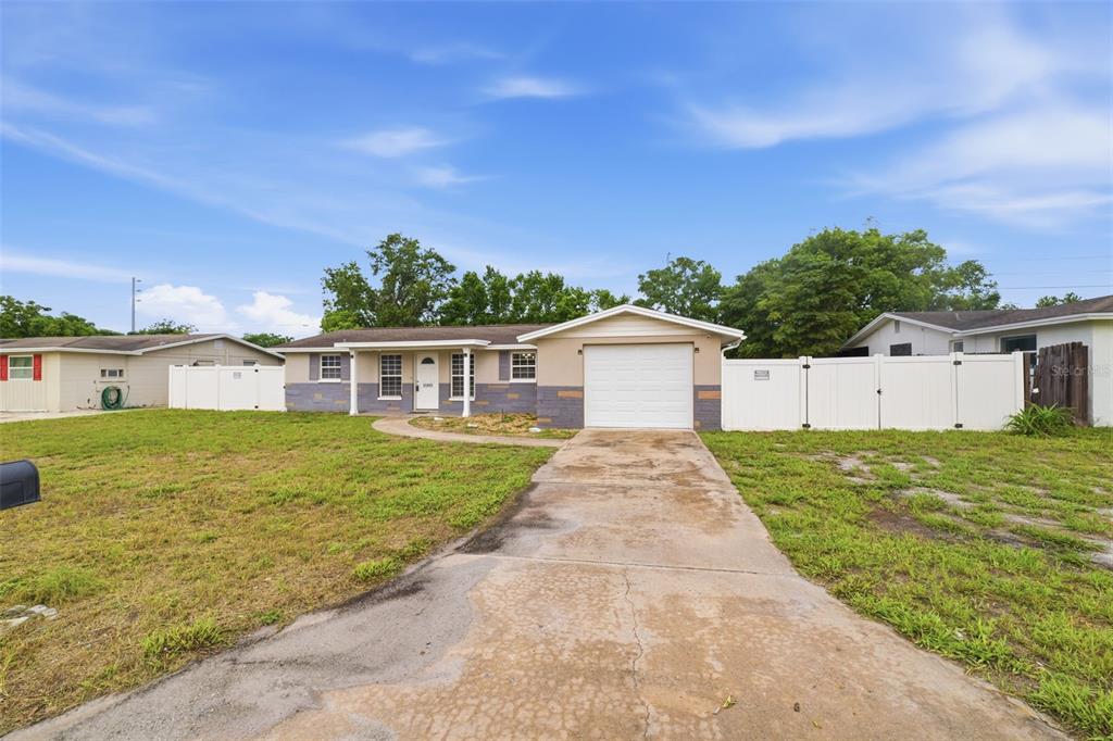 A single-story house with a white garage, gray stone accents, and a concrete driveway — 11105 ARECA DRIVE, PORT RICHEY, FL