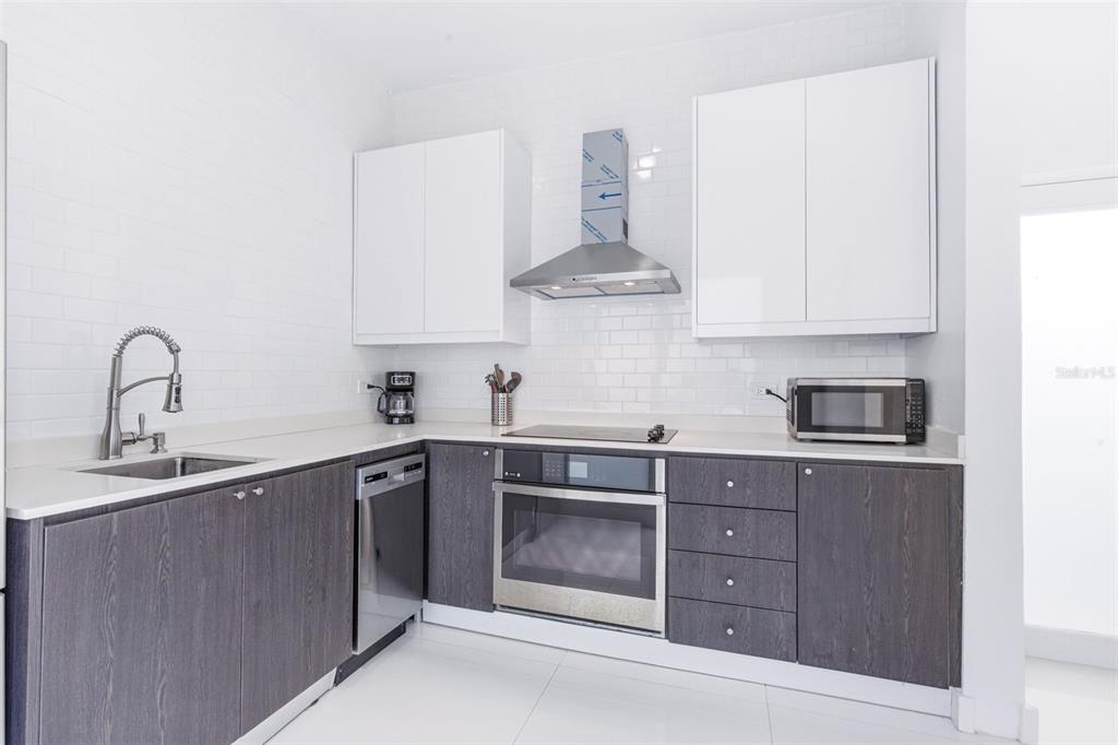 A modern kitchen features white upper cabinets, dark wood lower cabinets, and white subway tile — 56 CALLE F KRUG CONDADO UNIT Suite 1, SAN JUAN, PR