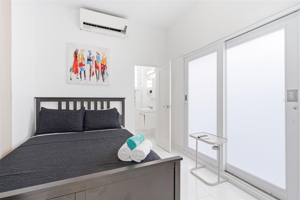 A bedroom features a dark bed frame, white tile floors, and a sliding glass door — 56 CALLE F KRUG CONDADO UNIT Suite 1, SAN JUAN, PR