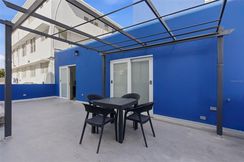 A patio features a black metal pergola, a small dining set, and bright blue walls — 56 CALLE F KRUG CONDADO UNIT Suite 1, SAN JUAN, PR