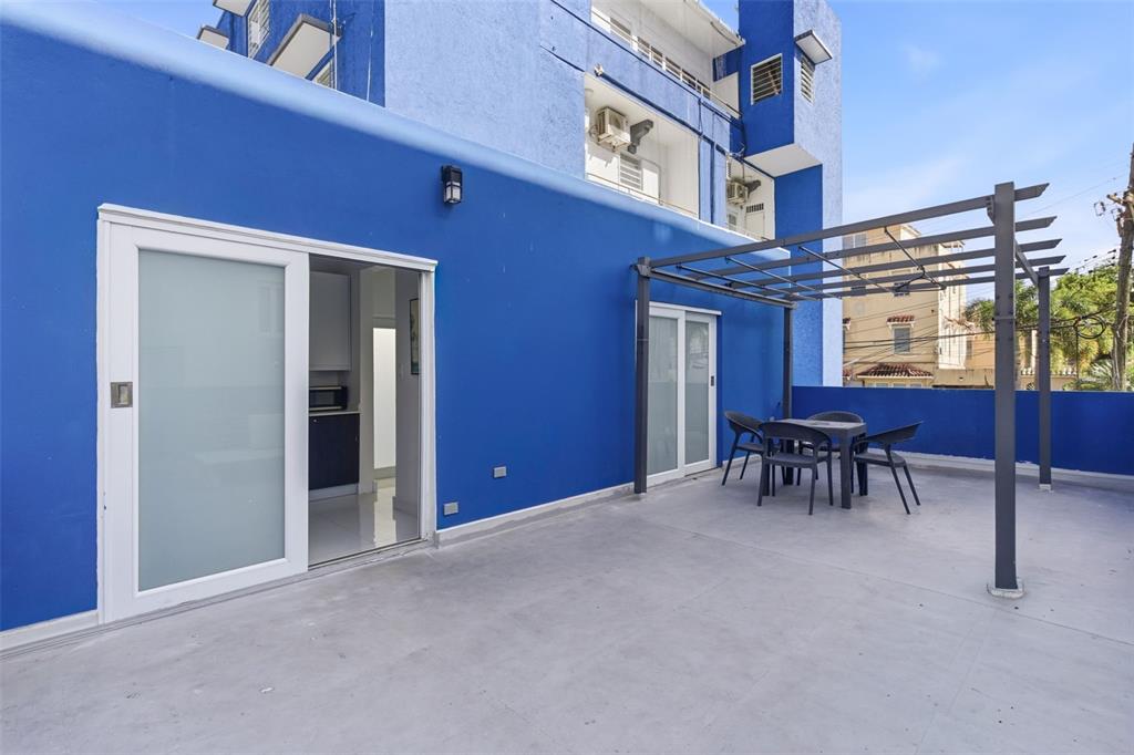 A blue exterior wall features a sliding glass door and a patio with a pergola — 56 CALLE F KRUG CONDADO UNIT Suite 1, SAN JUAN, PR