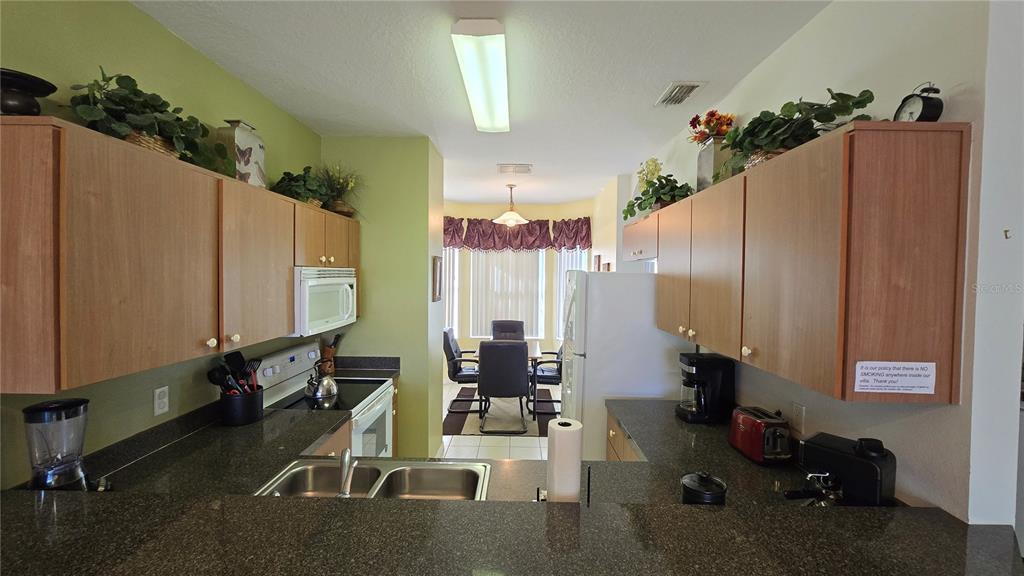 A kitchen with dark granite countertops, light wood cabinets, and a white dishwasher — 1213 SOUTH BEACH CIRCLE, KISSIMMEE, FL