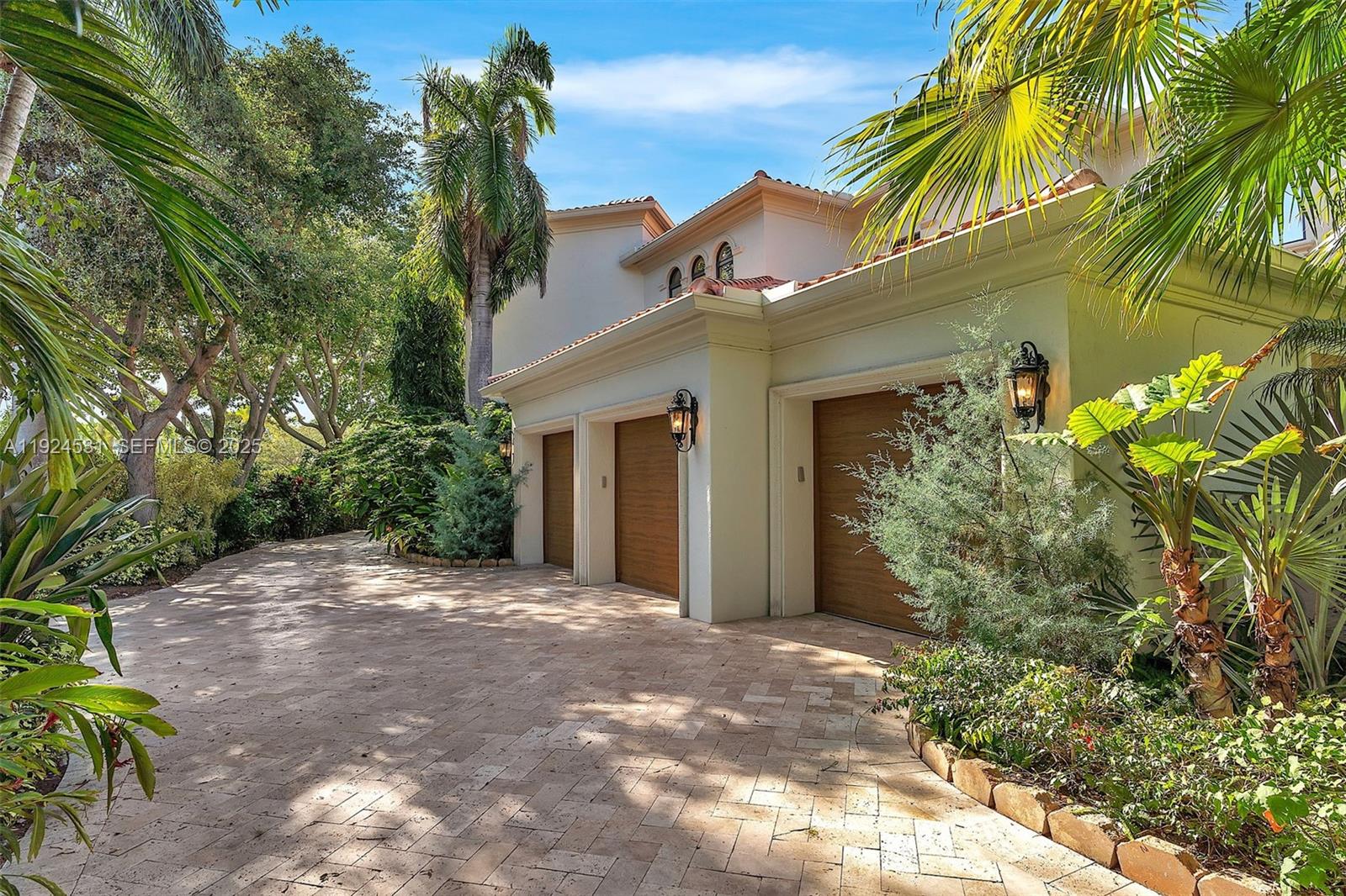 A three-car garage with wood-paneled doors sits at the end of a paved driveway — 4008 Sanctuary Ln, Boca Raton FL 33431, BOCA RATON, FL