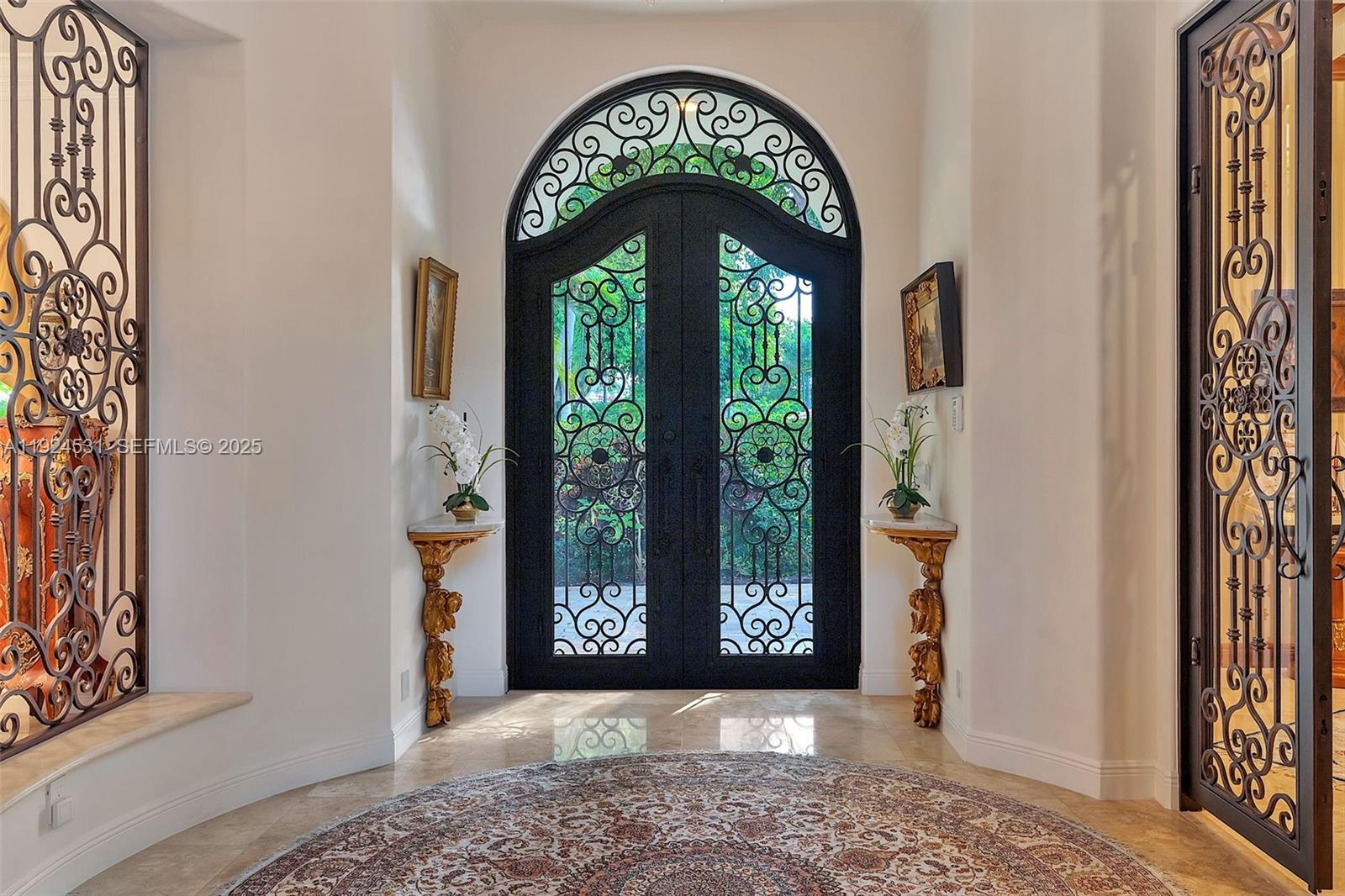 An entryway features a double arched iron door, ornate wall consoles, and a circular rug — 4008 Sanctuary Ln, Boca Raton FL 33431, BOCA RATON, FL