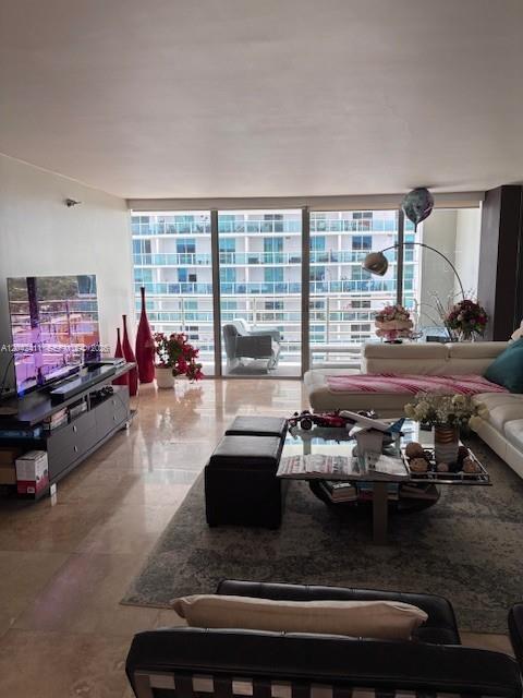 A living room features a large television, a glass coffee table, and floor-to-ceiling windows — 2025 Brickell Ave # 1903, Miami FL 33129, MIAMI, FL