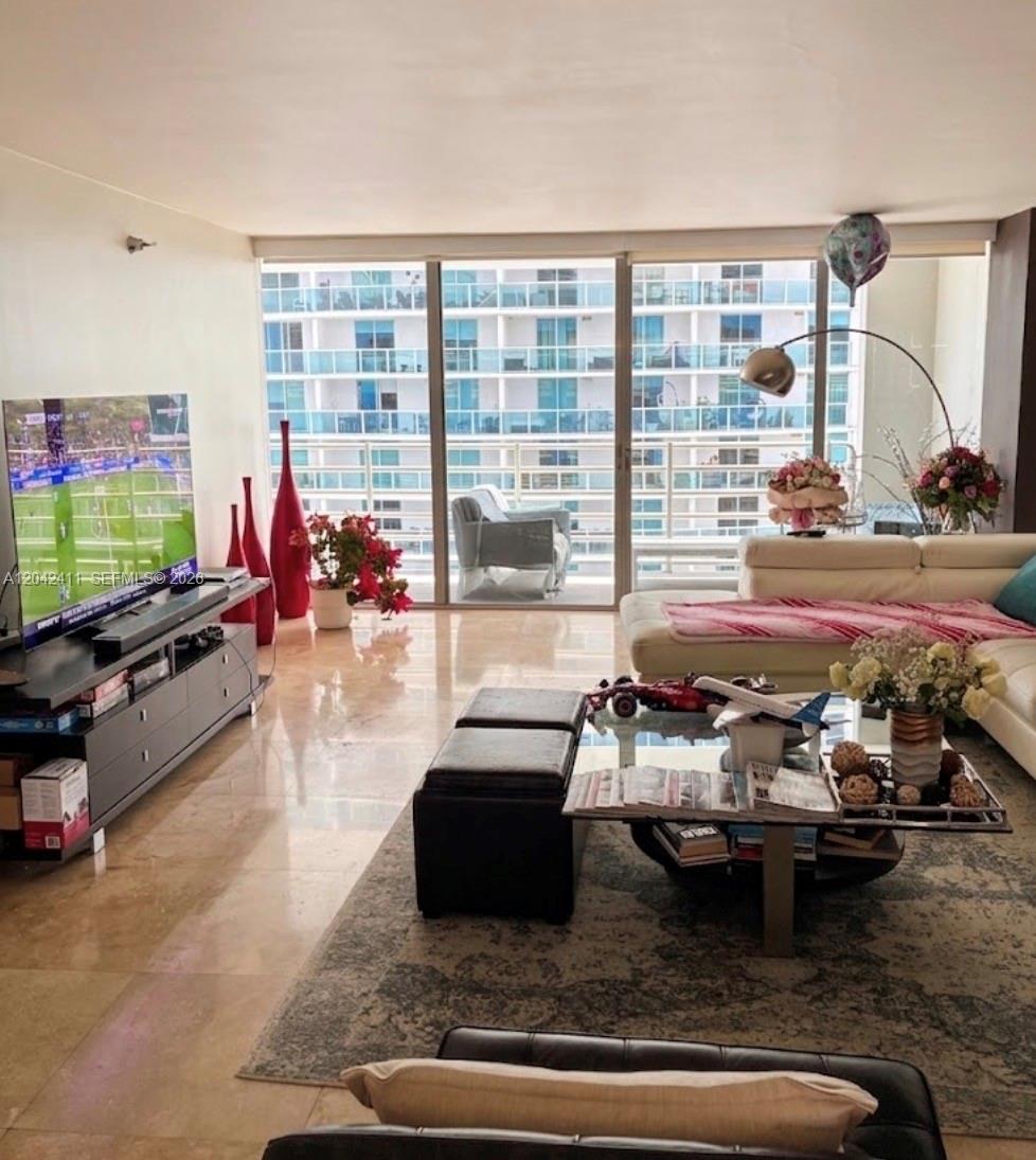 A living room features a white sectional sofa, a glass coffee table, and floor-to-ceiling windows — 2025 Brickell Ave # 1903, Miami FL 33129, MIAMI, FL