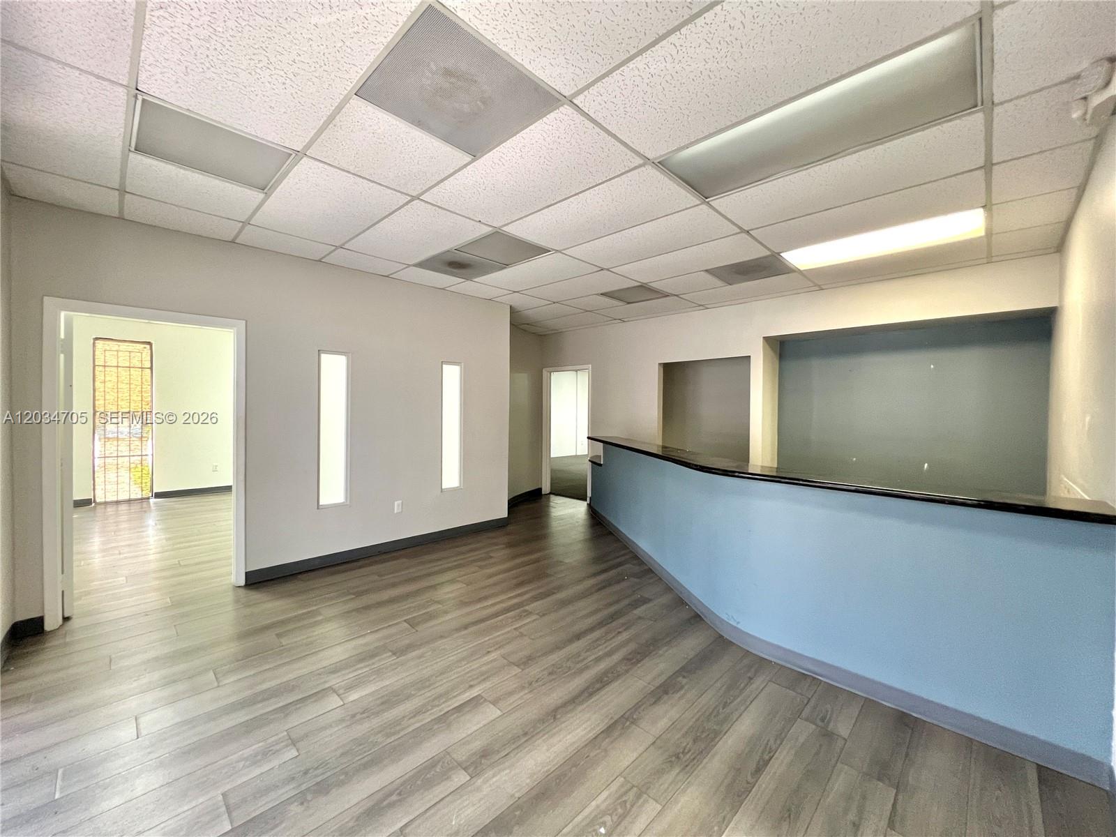 An office interior features a reception desk, wood-look flooring, and a drop ceiling — 3425 NW 73rd Ave, Miami FL 33122, MIAMI, FL