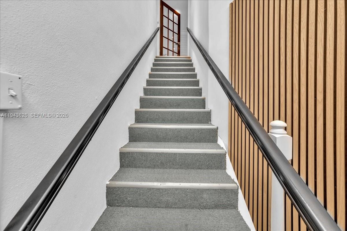 A carpeted staircase with black handrails leads to a doorway with a glass-paneled door — 500 NE 25th St # 10, Pompano Beach FL 33064, POMPANO BEACH, FL