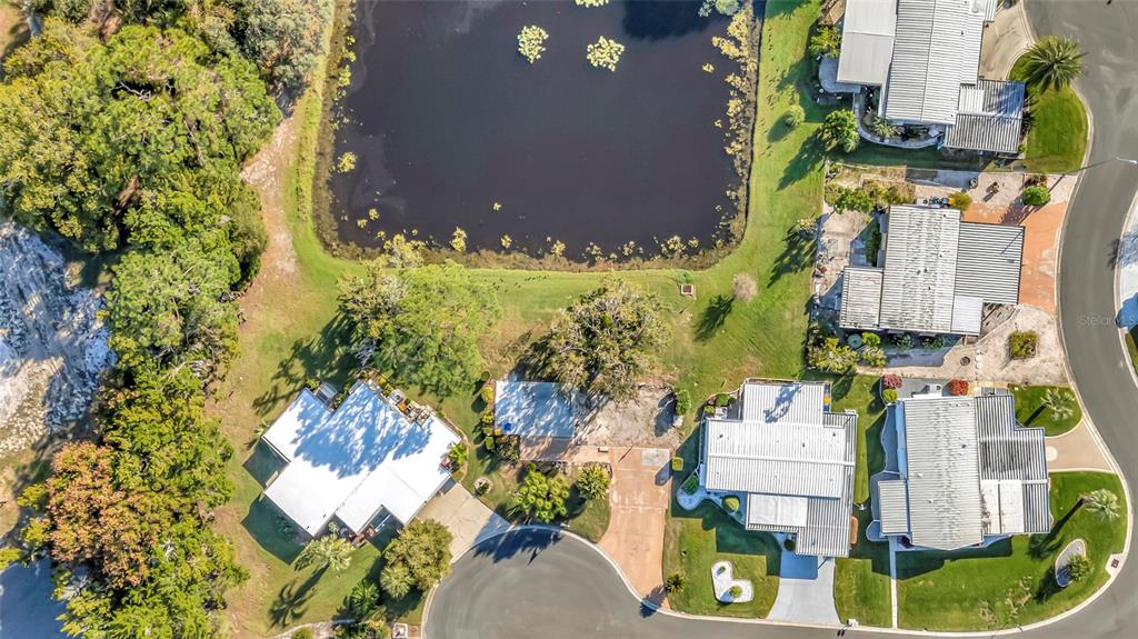 An aerial view shows several houses with white roofs situated around a pond and trees — 722 LANDRY LANE, TAVARES, FL