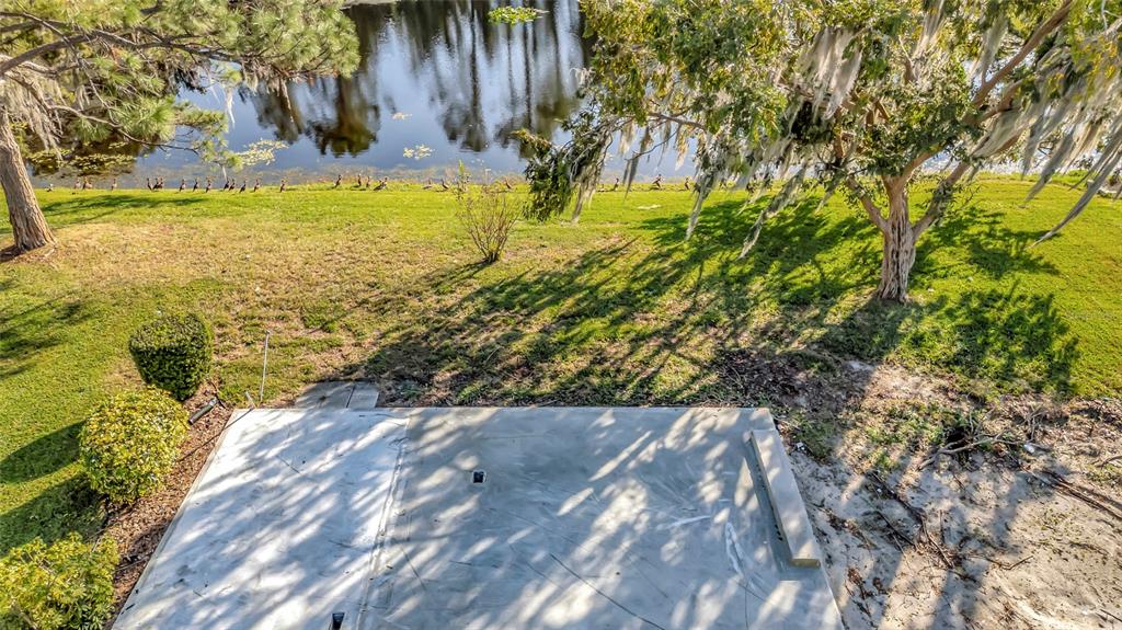 An elevated view of a concrete patio overlooking a grassy lawn and a small lake — 722 LANDRY LANE, TAVARES, FL