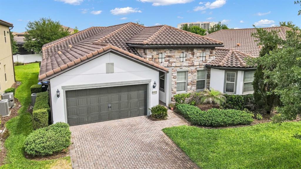 A single-story house with a stone facade, a two-car garage, and a paver driveway — 10944 CITRON OAKS DRIVE, ORLANDO, FL