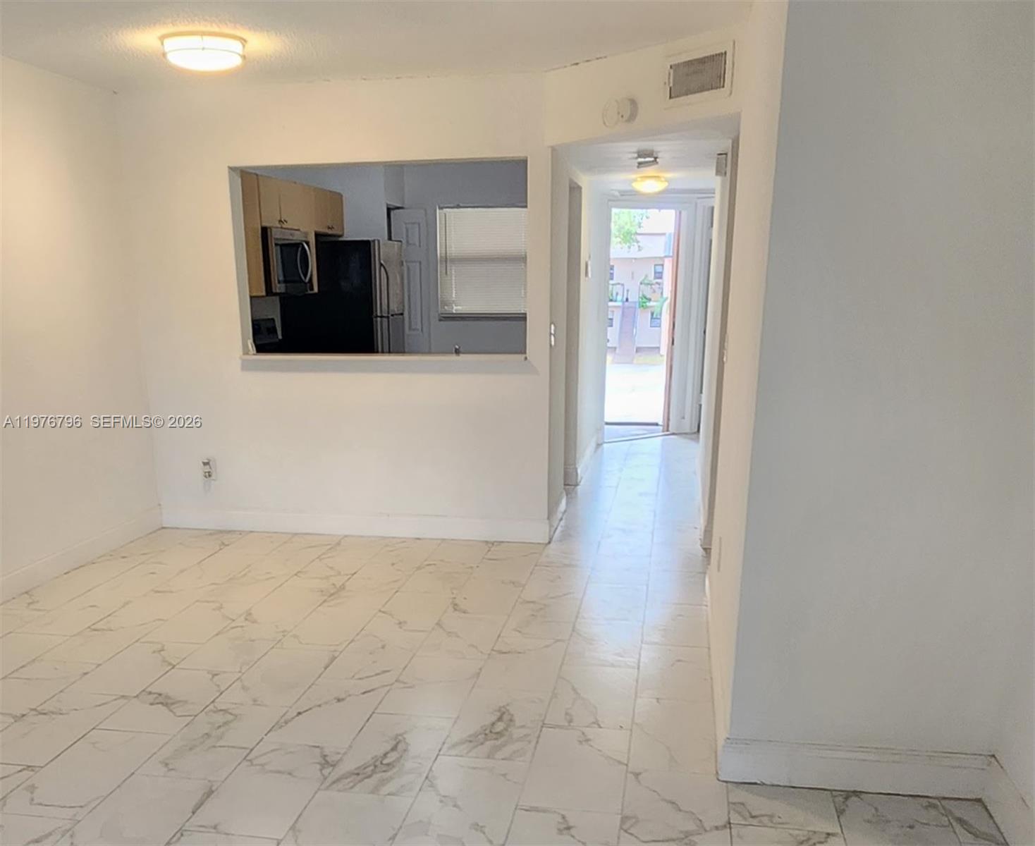 A room with white marble-look tile flooring features a pass-through window to the kitchen — 902 NE 209 St # 40, Miami FL 33179, MIAMI, FL