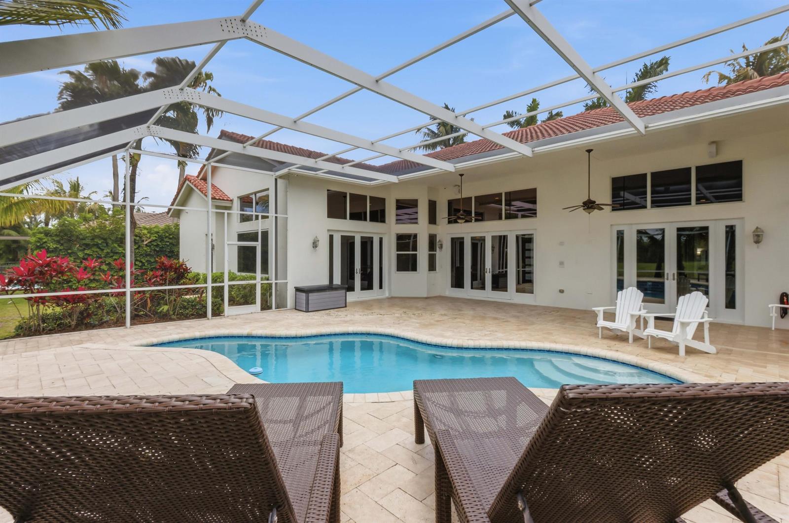 A screened-in patio features a kidney-shaped swimming pool, lounge chairs, and white exterior walls — 7079 NW 68th Drive, Parkland FL 33067, PARKLAND, FL