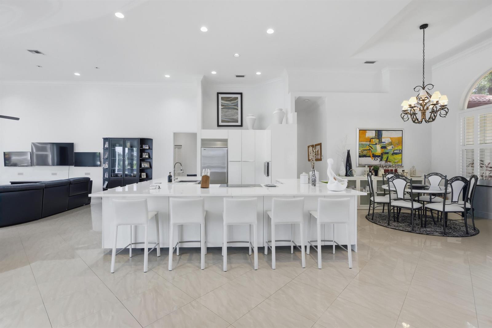 A bright, open-concept kitchen features a large white island with seating and adjacent dining area — 7079 NW 68th Drive, Parkland FL 33067, PARKLAND, FL