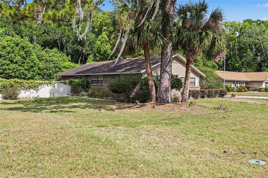 A single-story brick house with a brown roof sits behind a large grassy yard — 536 NE 40TH AVENUE, OCALA, FL