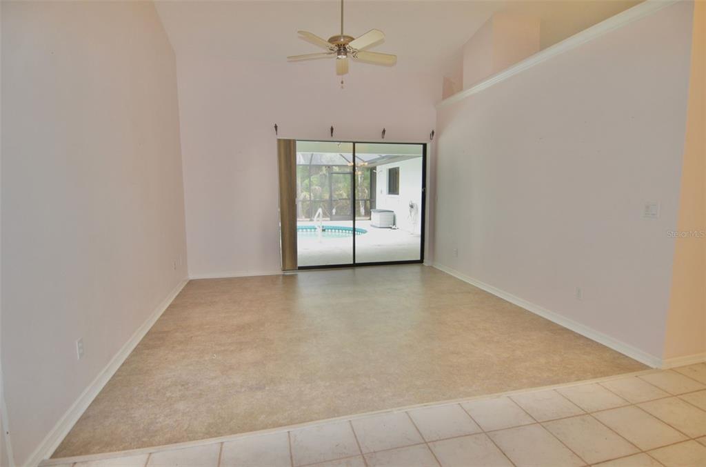 A living room with light-colored flooring, a ceiling fan, and sliding glass doors to a pool — 6514 N BISCAYNE DRIVE, NORTH PORT, FL